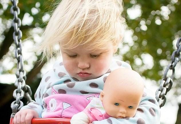 Fetița dormind în leagăn cu păpușa în brațe