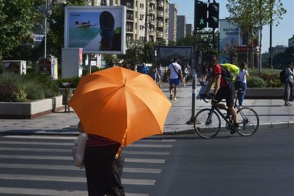 O femeie se protejeayă de razele soarelui cu o umbrelă