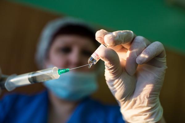 O asistentă medicală alimentează cu ser o seringă
