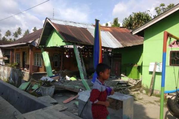 Copil în fața unei case distruse de cutremurul din Indonezia