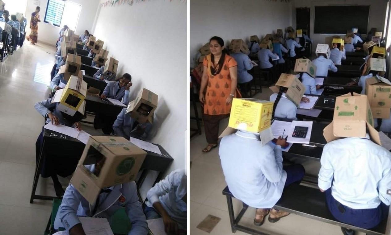 Elevii în bănci la examen cu cutii de carton pe cap