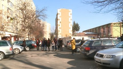 Tineri se plimbă pe o stradă, pe o vreme cu soare, în decembrie