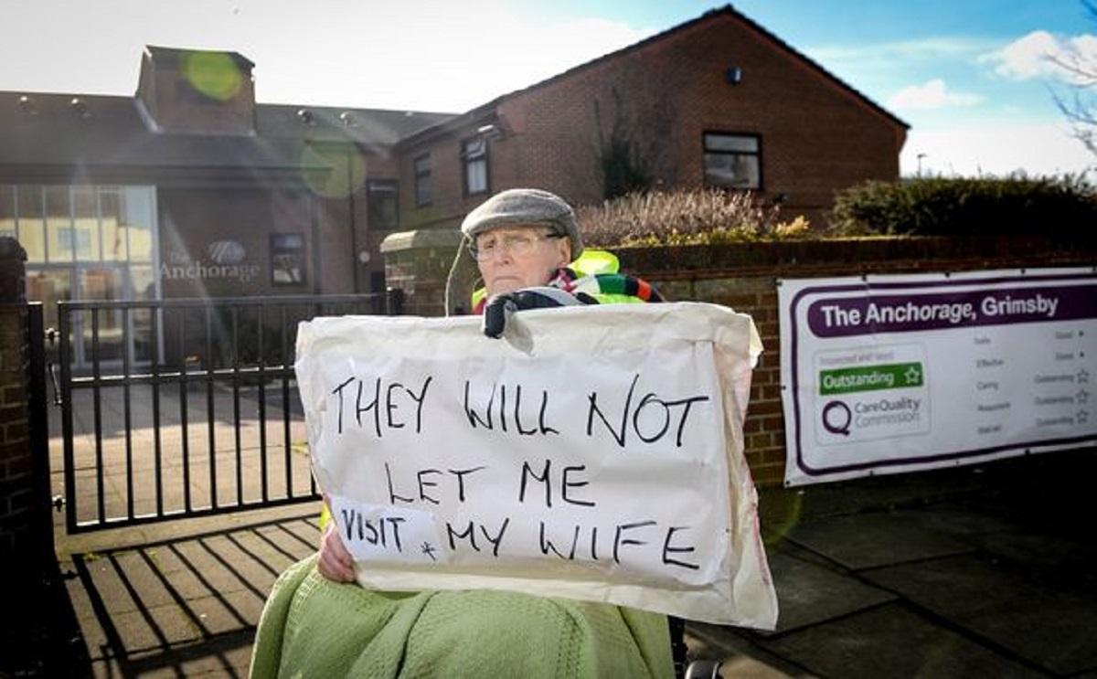 Bătrân care încearcă să-și apere soția Protest în fața unui azil, în Marea Britanie