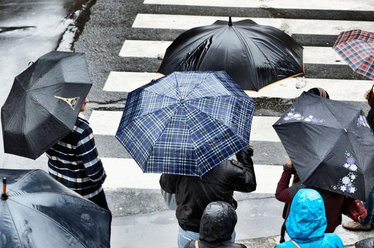 Ploaie într-un oraș, iar oamenii poartă umbrele
