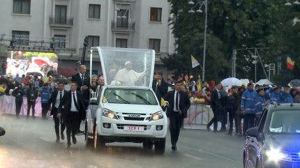 Papa Francisc în papamobil, pe ploaie în București