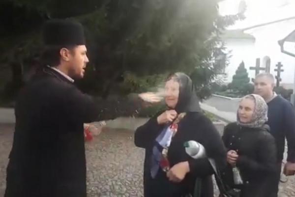 Credincioși stropiți peste față cu aghiasmă