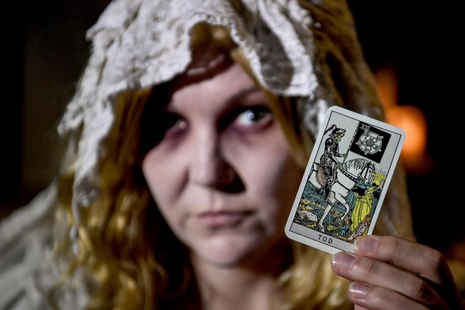 O vrăjitoare arată o carte de tarot Ţeapă cu vrăjitoare şi blesteme