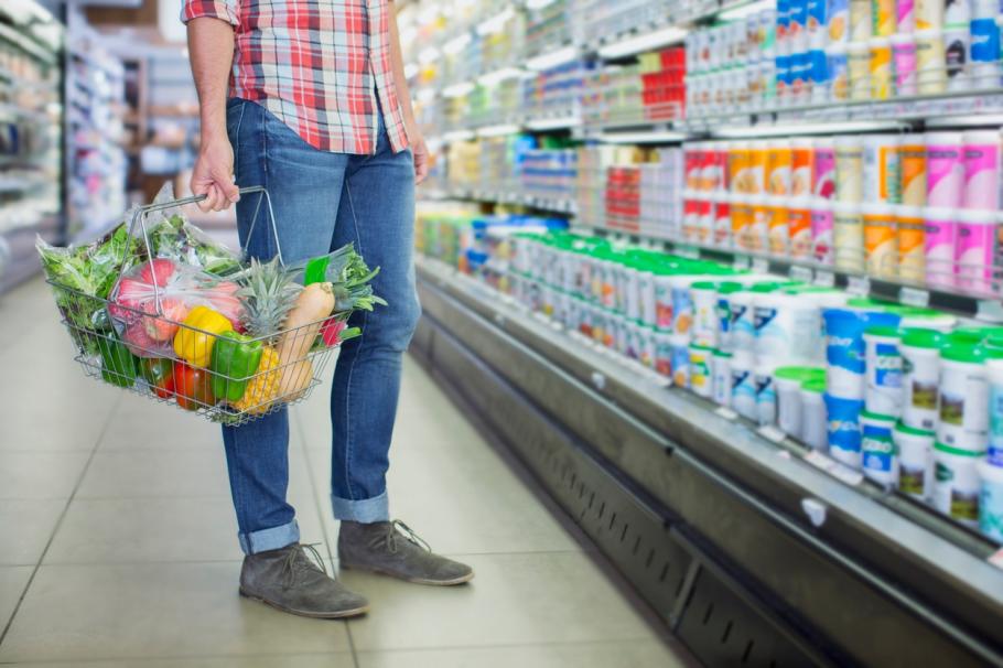 Un bărbat stă în fața rafturilor dintr-un magazin, cu un coș de cumpărături în mână Un bărbat stă în fața rafturilor dintr-un magazin, cu un coș de cumpărături în mână