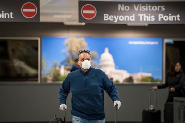 Un pasager cu mască și mănuși în aeroport