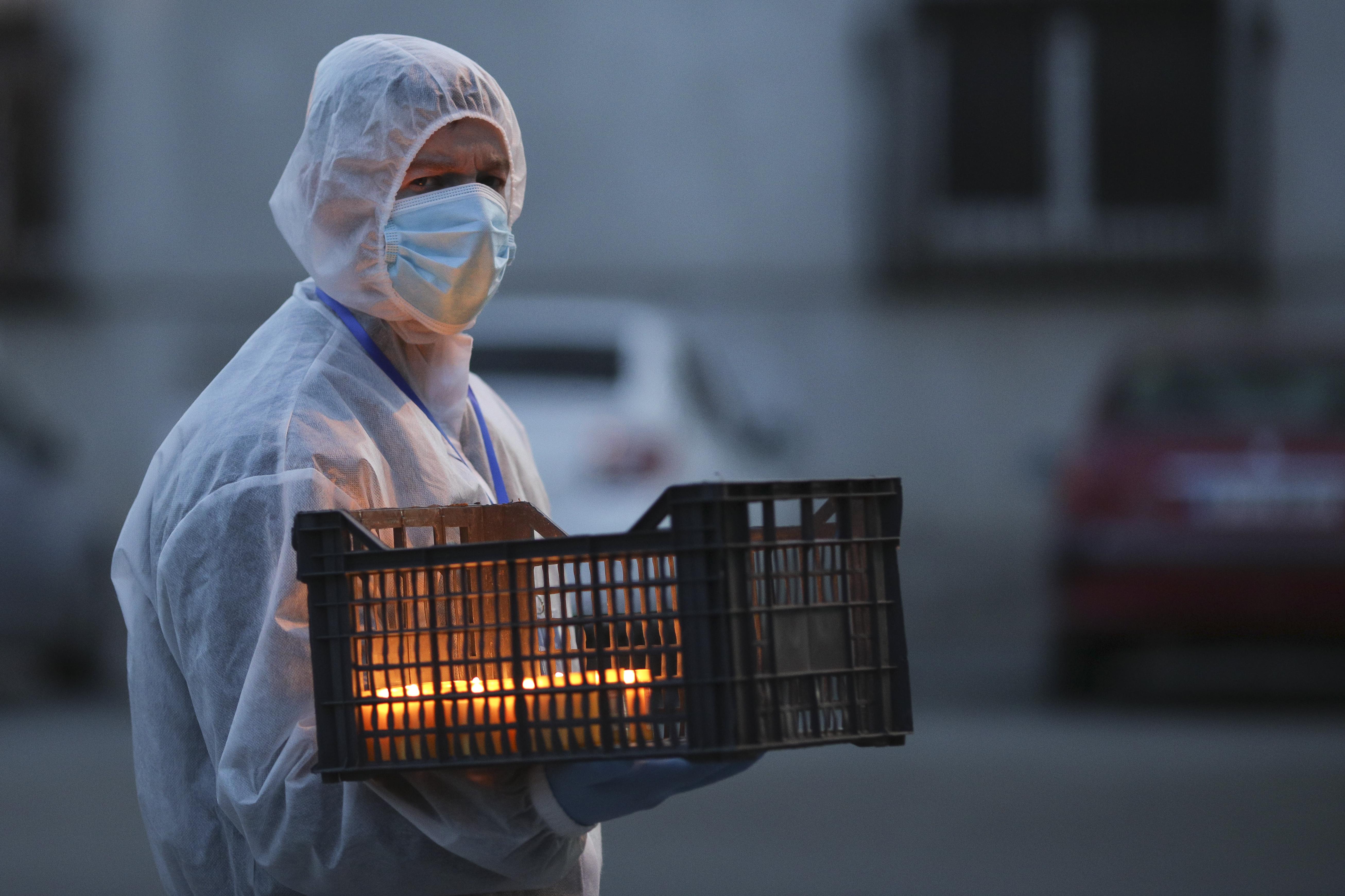 Voluntar ține în mână o ladă cu lumânări aprinse