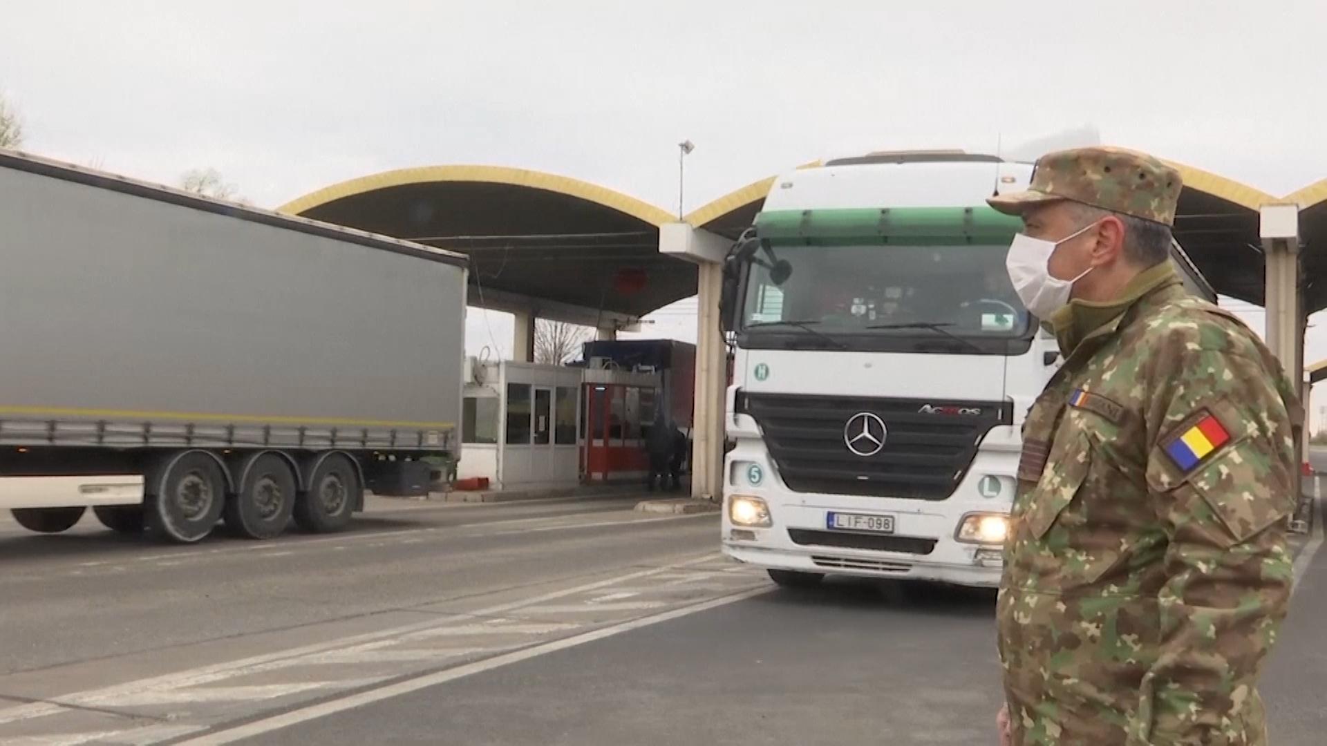 Militar cu mască lângă TIR-uri care intră în vama din România