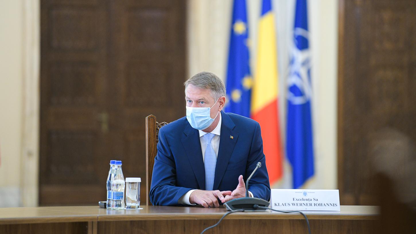 Klaus Iohannis la masa de ședință vorbește participanților