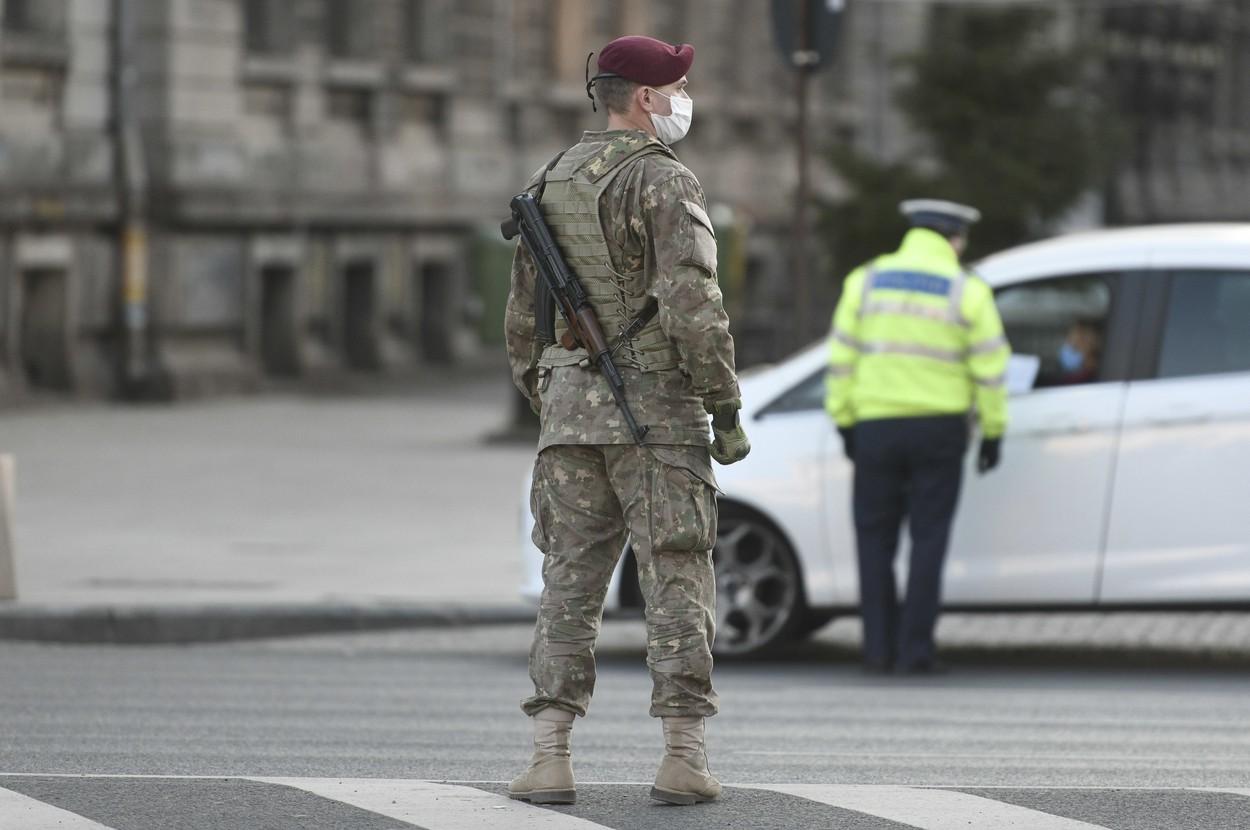 Militar pe stradă lângă un polițist care face controale