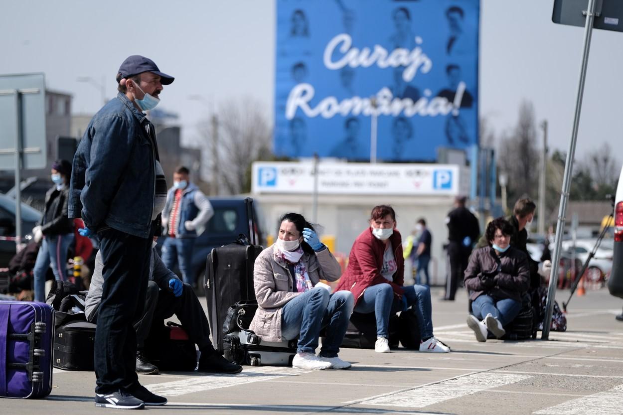 Muncitori români stau pe bagaje în fața aeroportului