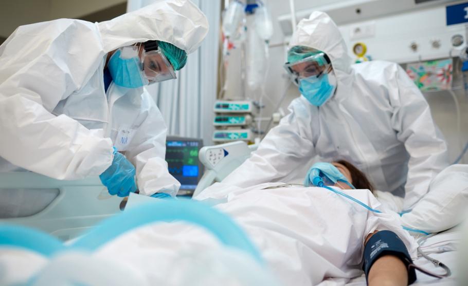 Medici în combinezoane Medici în combinezoane tratează pacient pe patul de spital