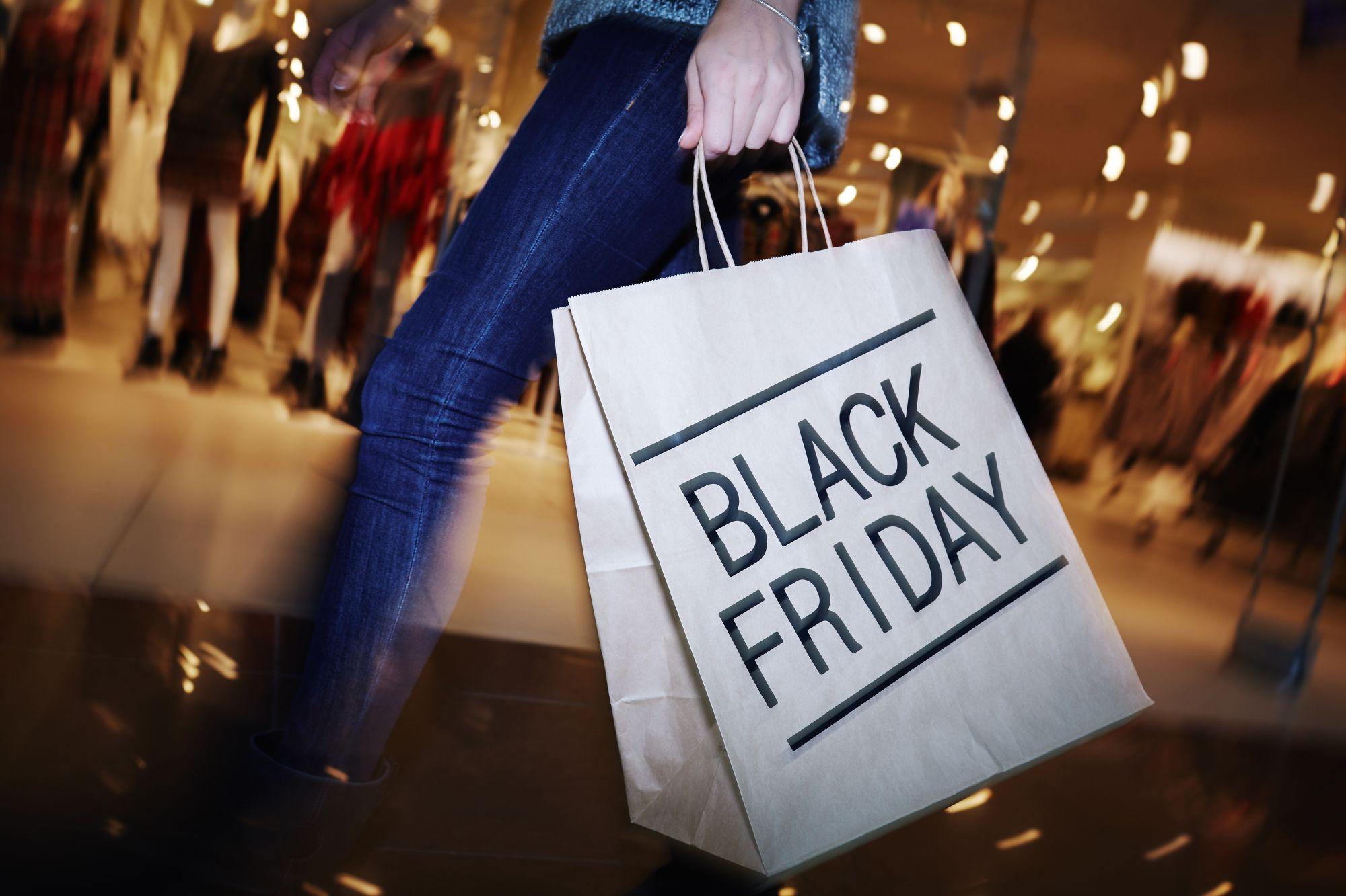 O femeie ţine o pungă de hârtie pe care sunt inscripţionate cuvintele Black Friday