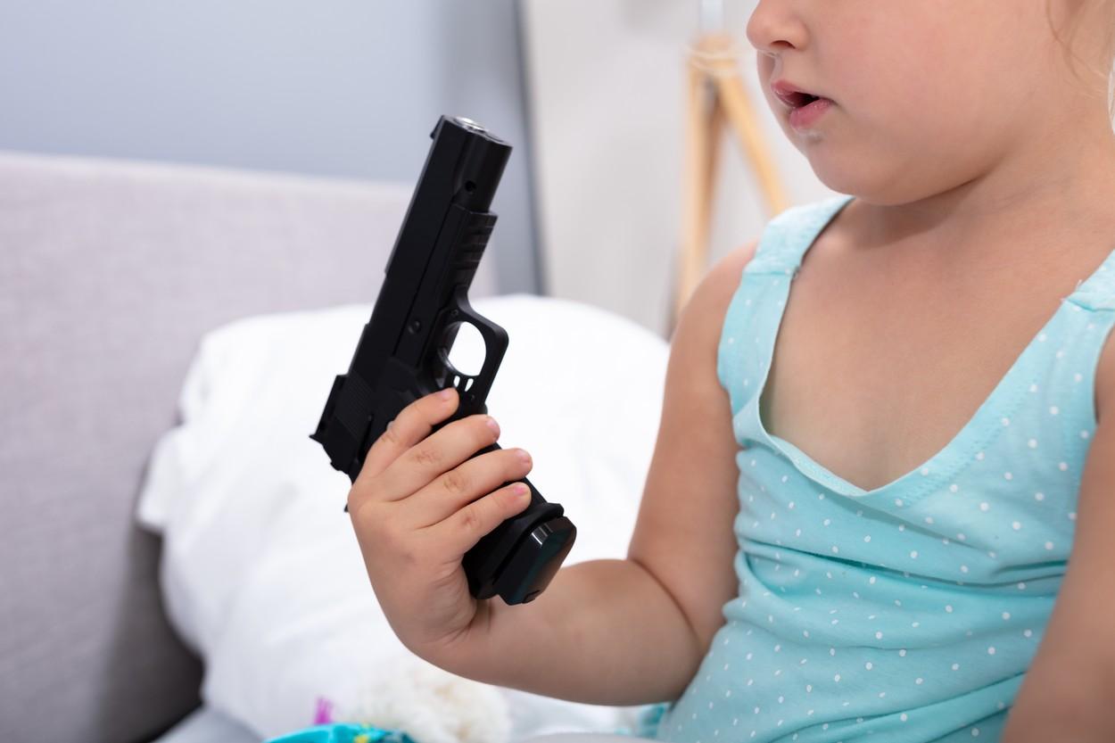 Fetiţă care ţine în mână un pistol