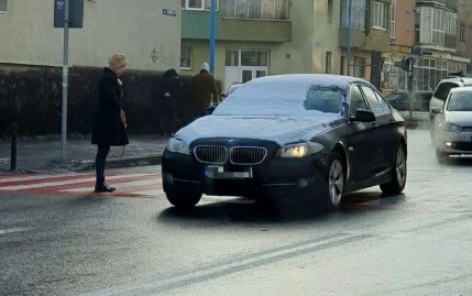 Femeia priveşte cum BMW-ul trece pe lângă ea fără să îi acorde prioritate