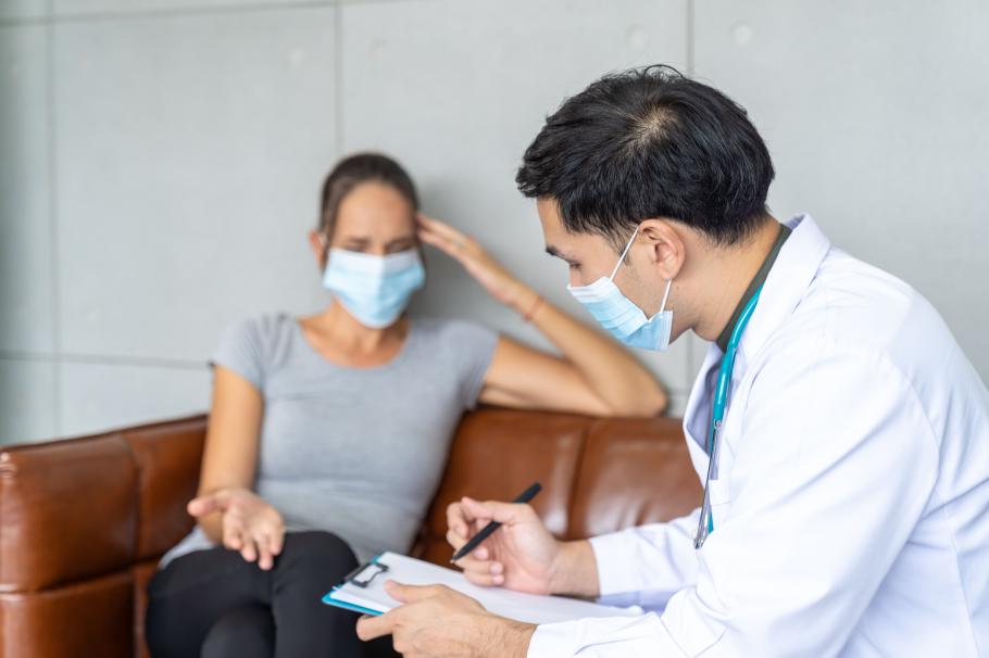 Bilanț coronavirus în România, 20 decembrie. Un doctor cu mască de protecție consultă o pacientă și notează