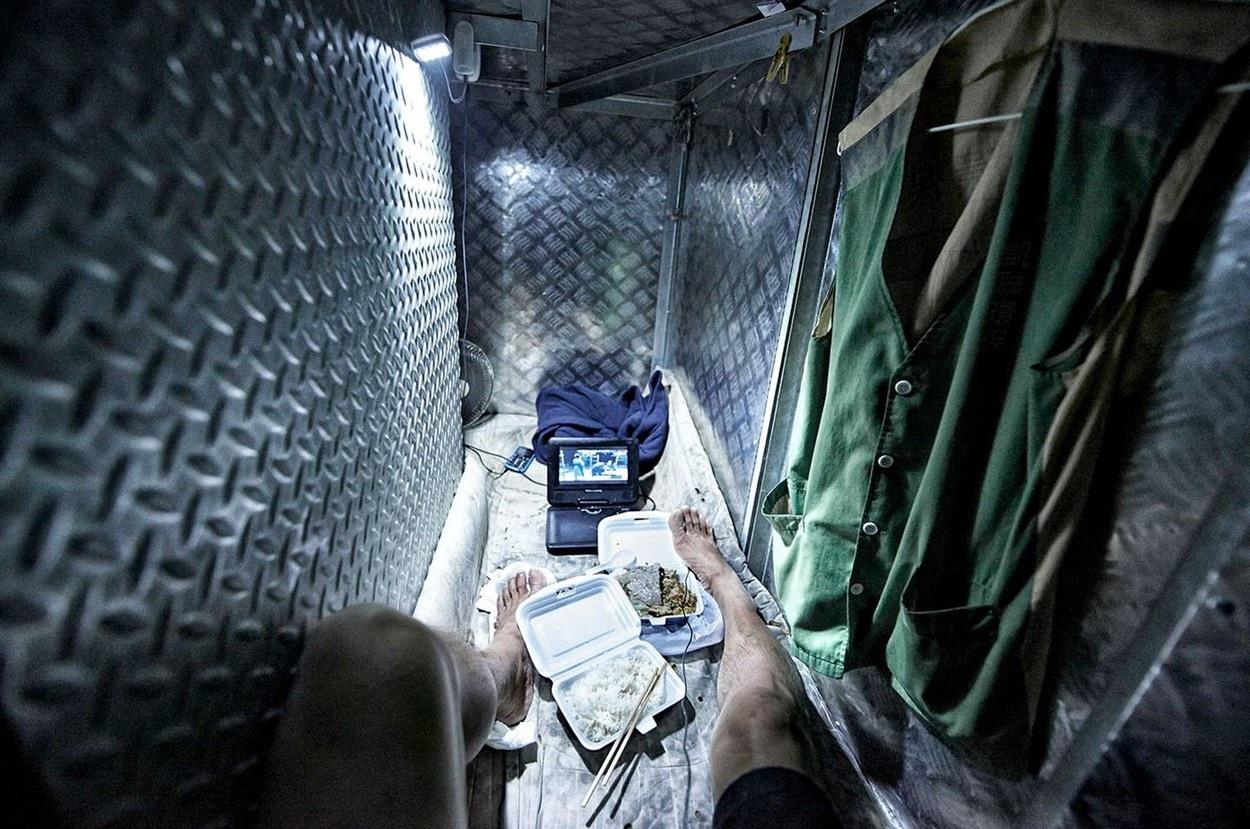 Hong Kong: Un bărbat stă într-un spaţiu minuscul, mănâncă din caserole şi se uită la un televizor mic