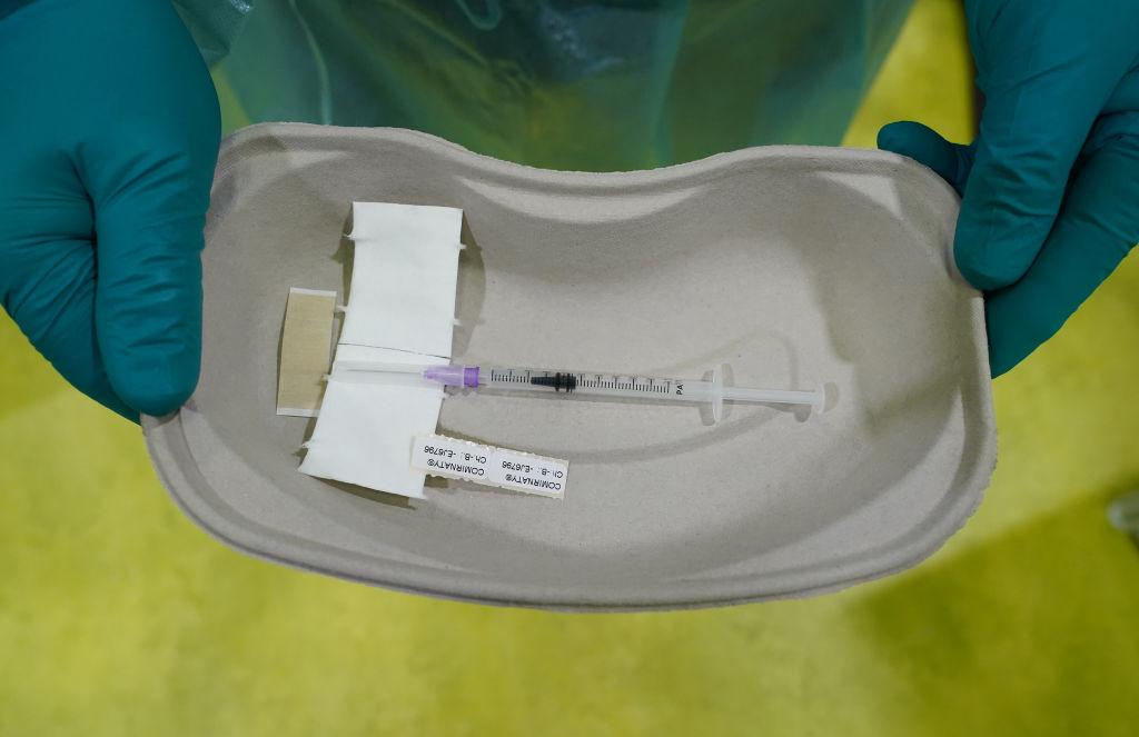 Un cadru medical ține într-o tăviță o seringă care conține o doză de vaccin Pfizer