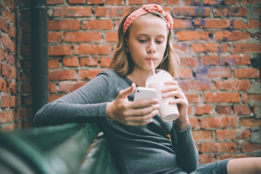 Instagram va interzice adulţilor să trimită mesaje adolescenţilor cu care nu sunt prieteni O tânără îşi foloseşte telefonul mobil în timp ce bea cu paiul dintr-o băutură răcoritoare