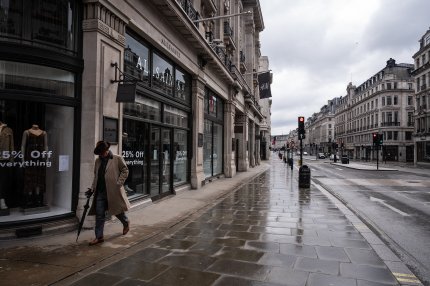 Un bărbat pășeste pe Regent Street din Londra, prin fața magazinelor închise