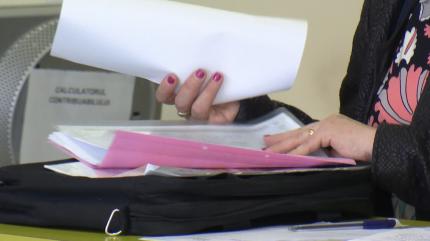 O angajată verifică actele depuse la dosar de un contribuabil