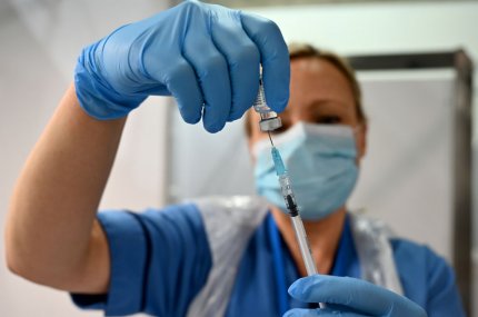 O asistență ține în mână o serigă cu vaccinul împotriva Covid-19