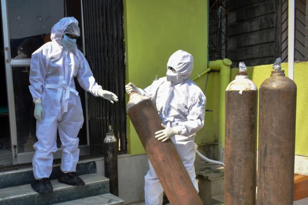 Medici în costum de protecţie transportă recipiente de oxigen în spital
