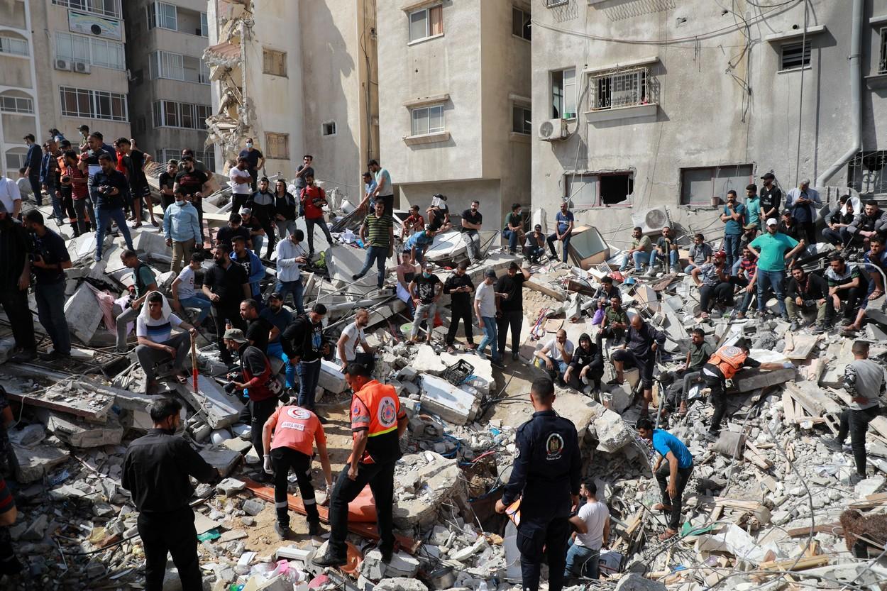 Oamenii s-au adunat pe ruinele unui bloc din Gaza, distrus în urma bombardamentelor
