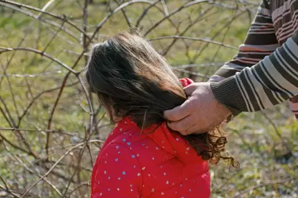 Fetiţă omorâtă În imagine: Mâinile unui bărbat cuprind părul unei fetițe