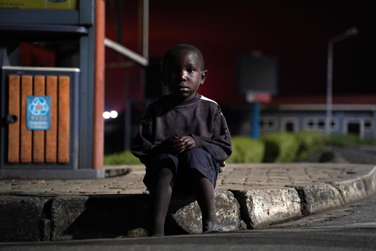 Un copil pierdut stă pe o bordură în timp ce congolezii fug de Goma, Republica Democrată Congo (RDC), după erupția vulcanului Nyiragongo, la punctul de frontieră cunoscut sub numele de „Petite Barriere” din Gisenyi, Ruanda, pe 23 mai 2021.