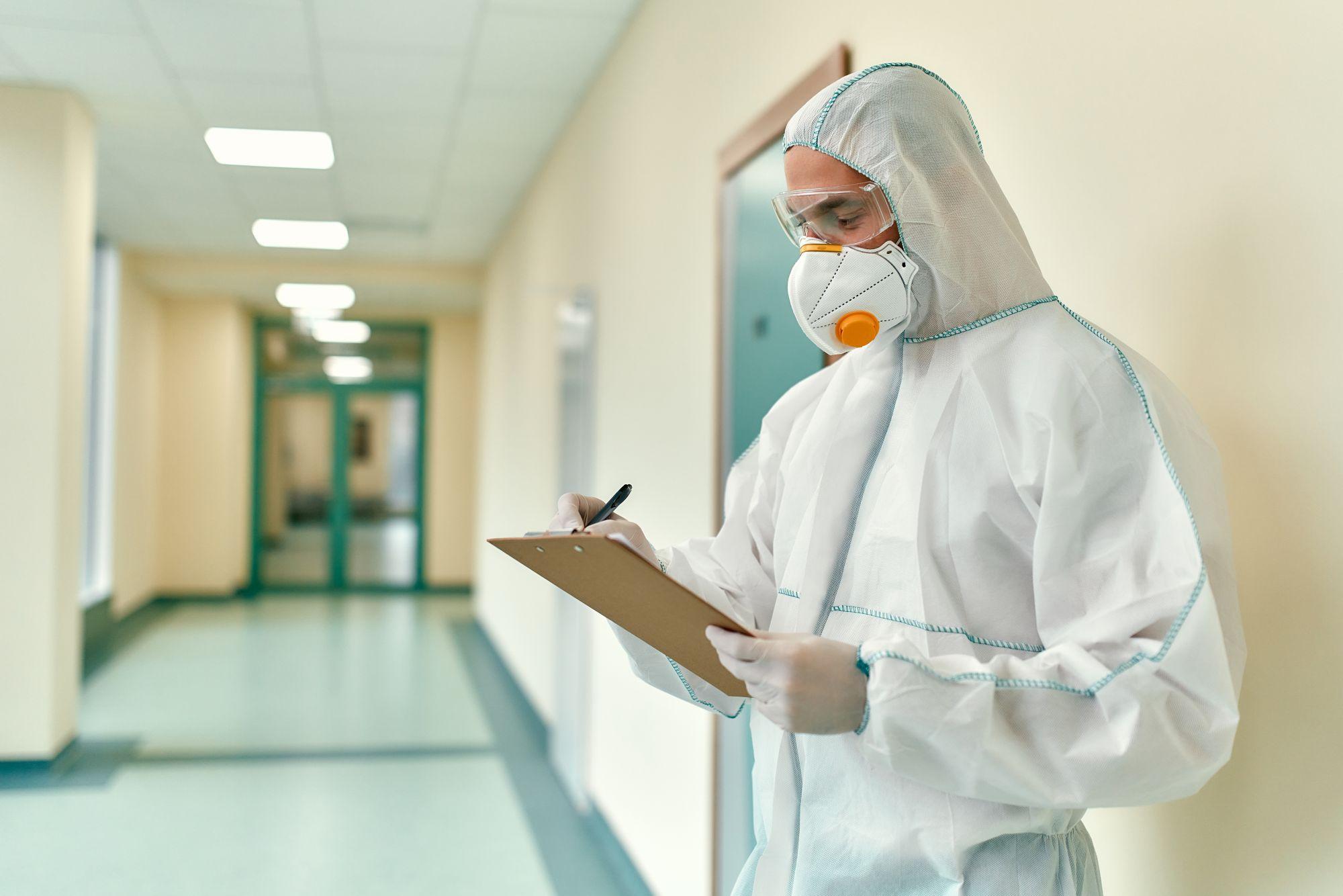 Un doctor echipat pentru protecţie împotriva Covid ia notiţe pe holul unui spital