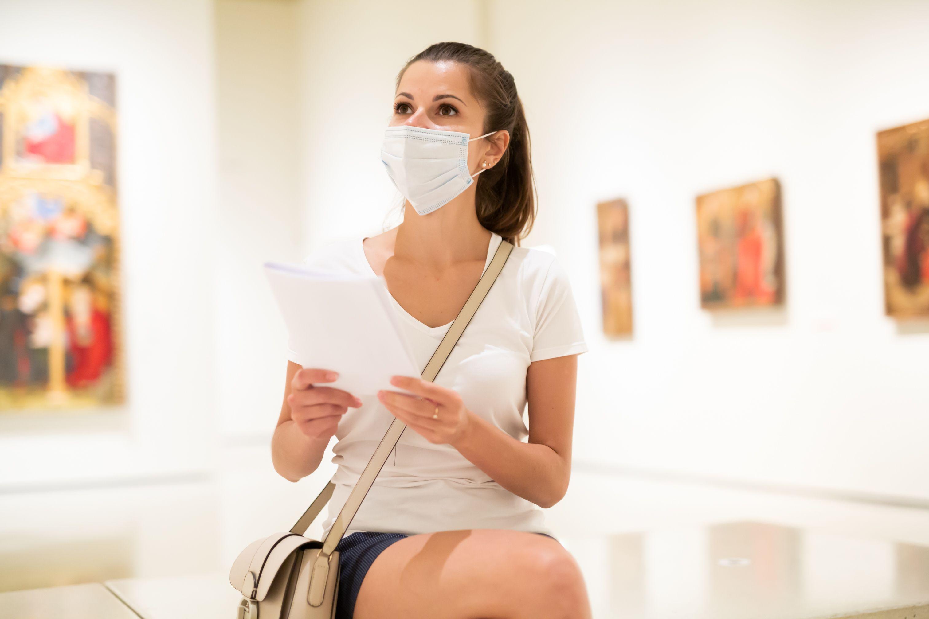 O tânără cu mască de protecție la o galerie de artă