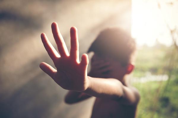 Băiat speriat care îşi acoperă faţa cu mâna
