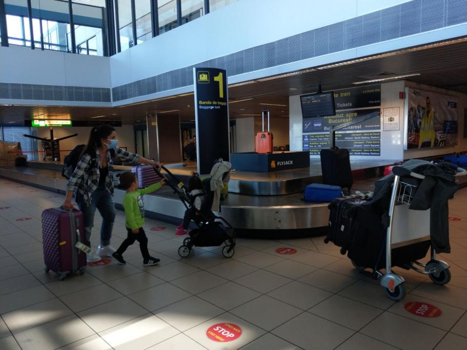 Pasagerii cu certificat digital european pentru COVID-19 nu mai trec prin controlul DSP din Aeroportul Otopeni O femeie cu mască pe față este însoțită de doi copii, pe Aeroportul Internațional Henri Coandă Otopeni