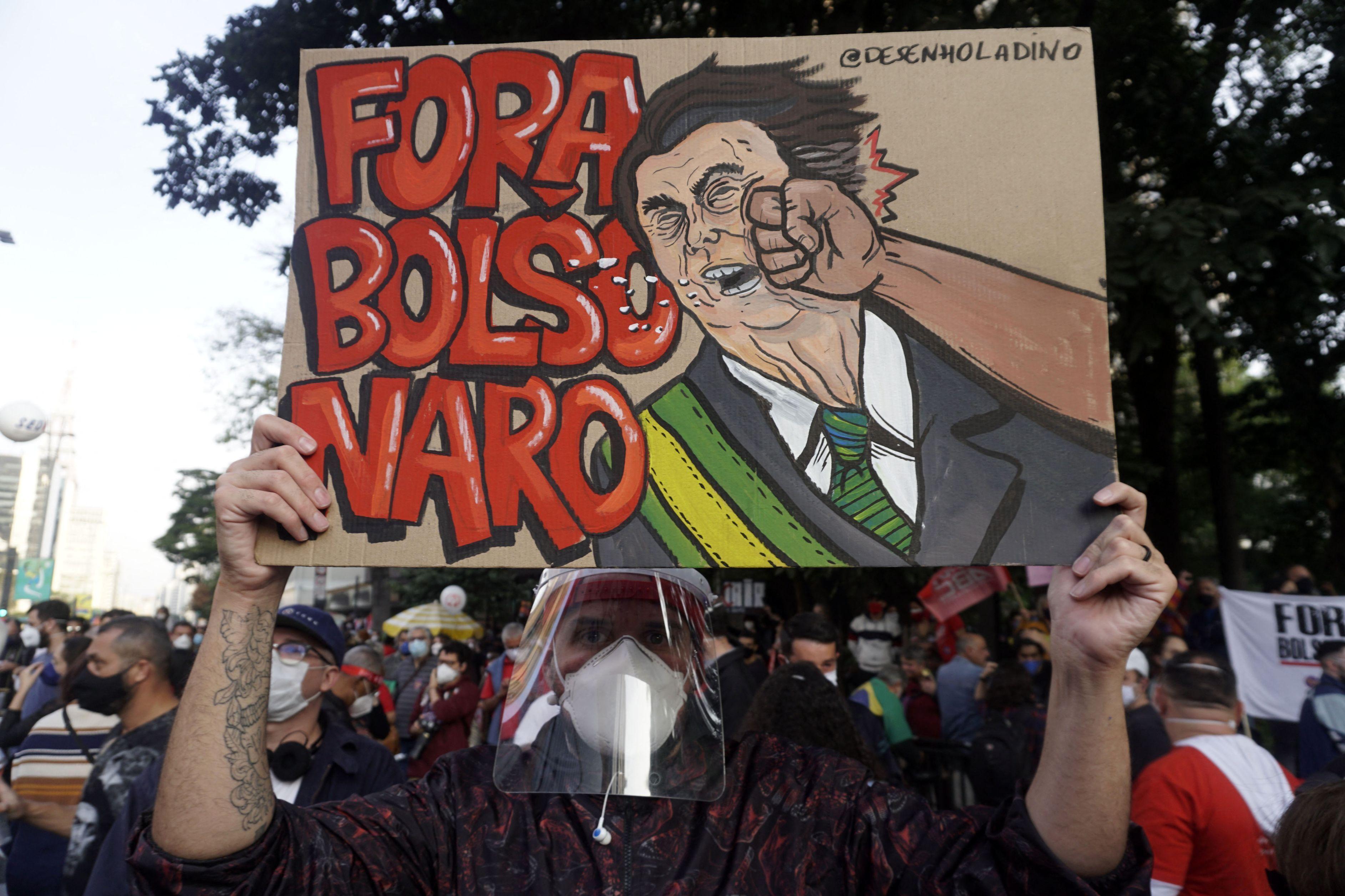 Oamenii au participat la demonstraţii împotriva lui Jair Bolsonaro, pe care îl acuză de modul în care a acţionat în pandemia covid Banner anti-Jair Bolsonaro, la un protest din Brazilia