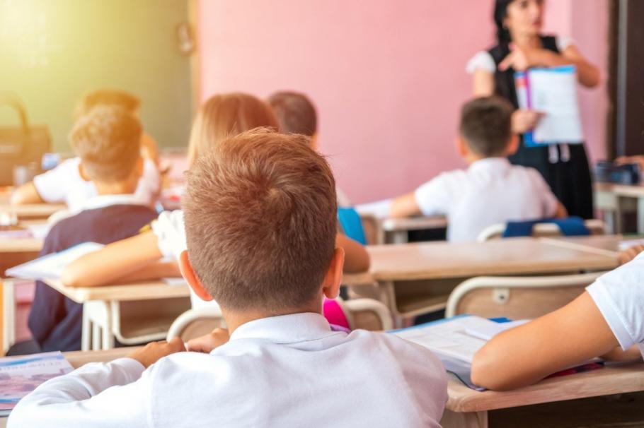 Un învăţător nevaccinat a îmbolnăvit mai bine de jumătate dintre elevii săi de școală primară, după ce și-a scos masca să le citească o poveste, în California Un invatator le arată un manual elevilor de clasa primara