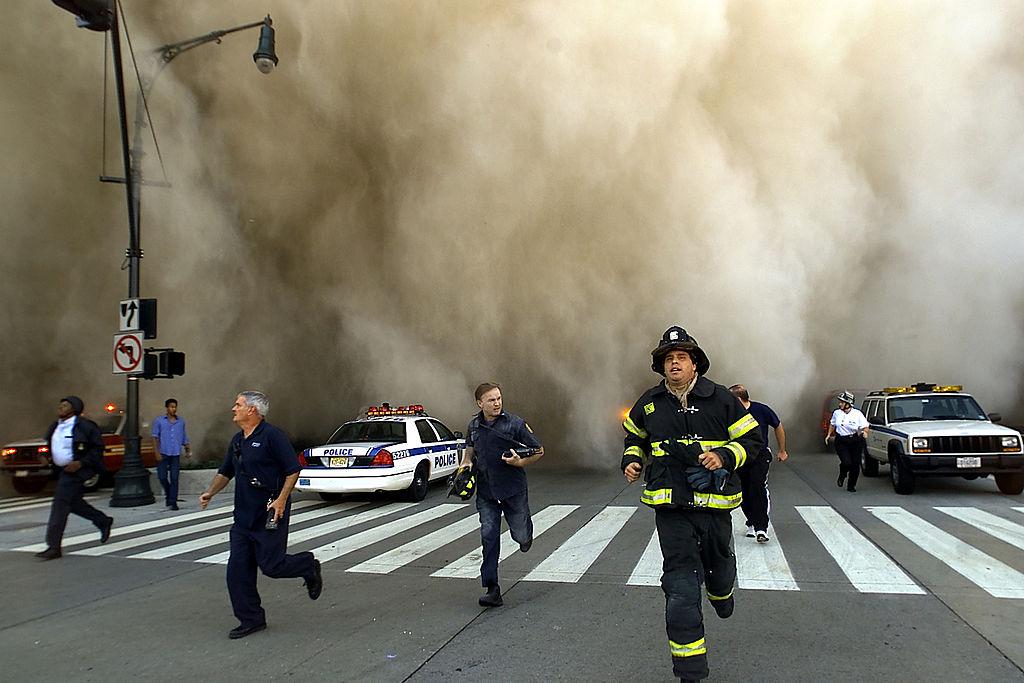 Polițiștii și pompierii fug de imensul nor de praf cauzat în timp ce primul turn al World Trade Center se prăbușește, 11septembrie 2001