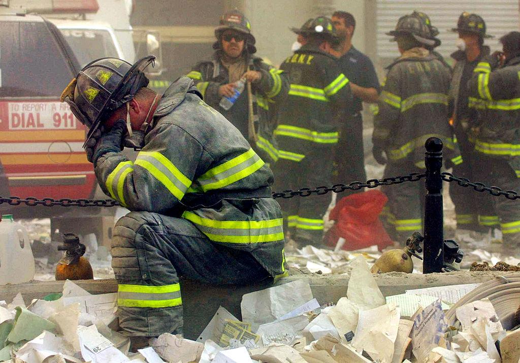 Un pompier se aşează în genunchi pentru a-şi şterge lacrimile, după prăbuşirea Turnurilor Gemene, 11 septembrie 2001