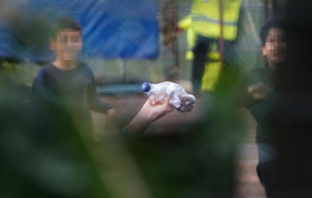 Tânăra se afla într-un grup de copii care au trecut pe lângă agenții de pază și au fugit spre gard pentru a arunca sticla fotografului.