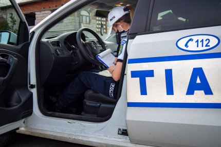 O femeie poliţist scrie o amendă de circulaţie, stând pe scaunul şoferului în autospeciala de poliţie