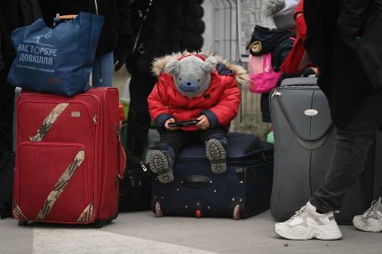 Un copil se joaca cu telefonul mobil dupa ce au traversat Dunarea, cu feribotul, la Isaccea, punct de frontiera intre Ucraina si Romania