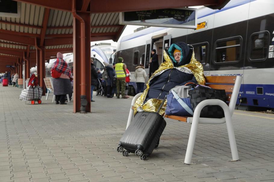 Femeie bătrână, învelită într-o pătură, pe obancă, în gară - Ucraina