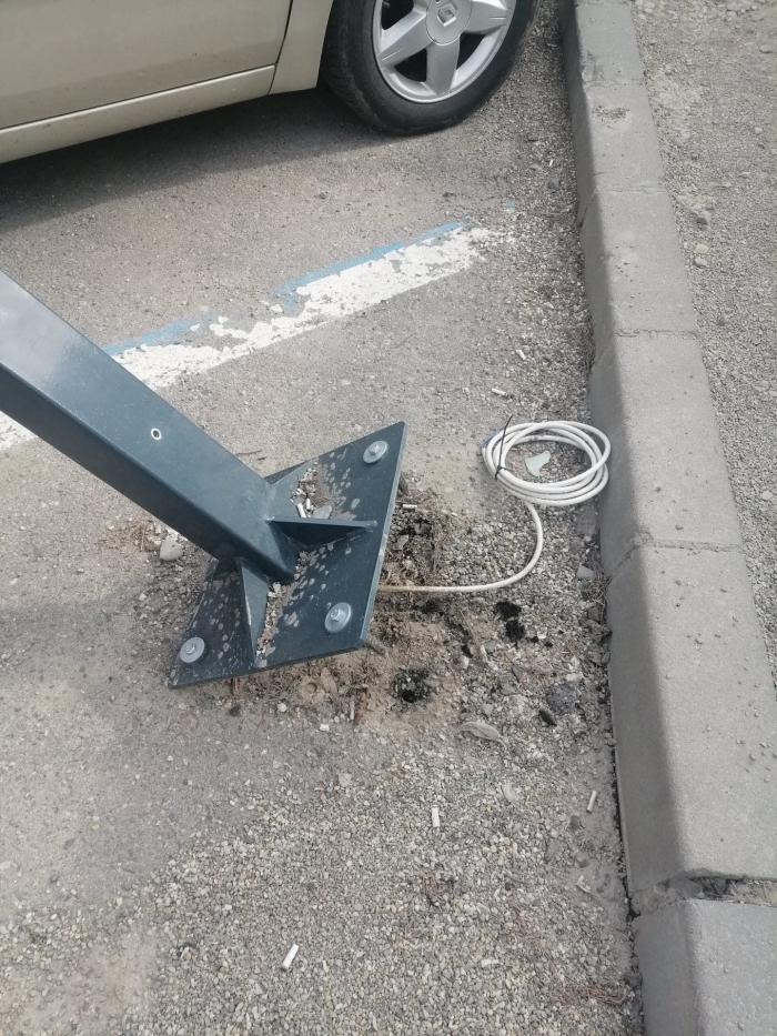 O maşină parcată, avariată de un indicator electronic montat recent. Piciorul de metal, prins în asfalt cu dibluri de tablouri