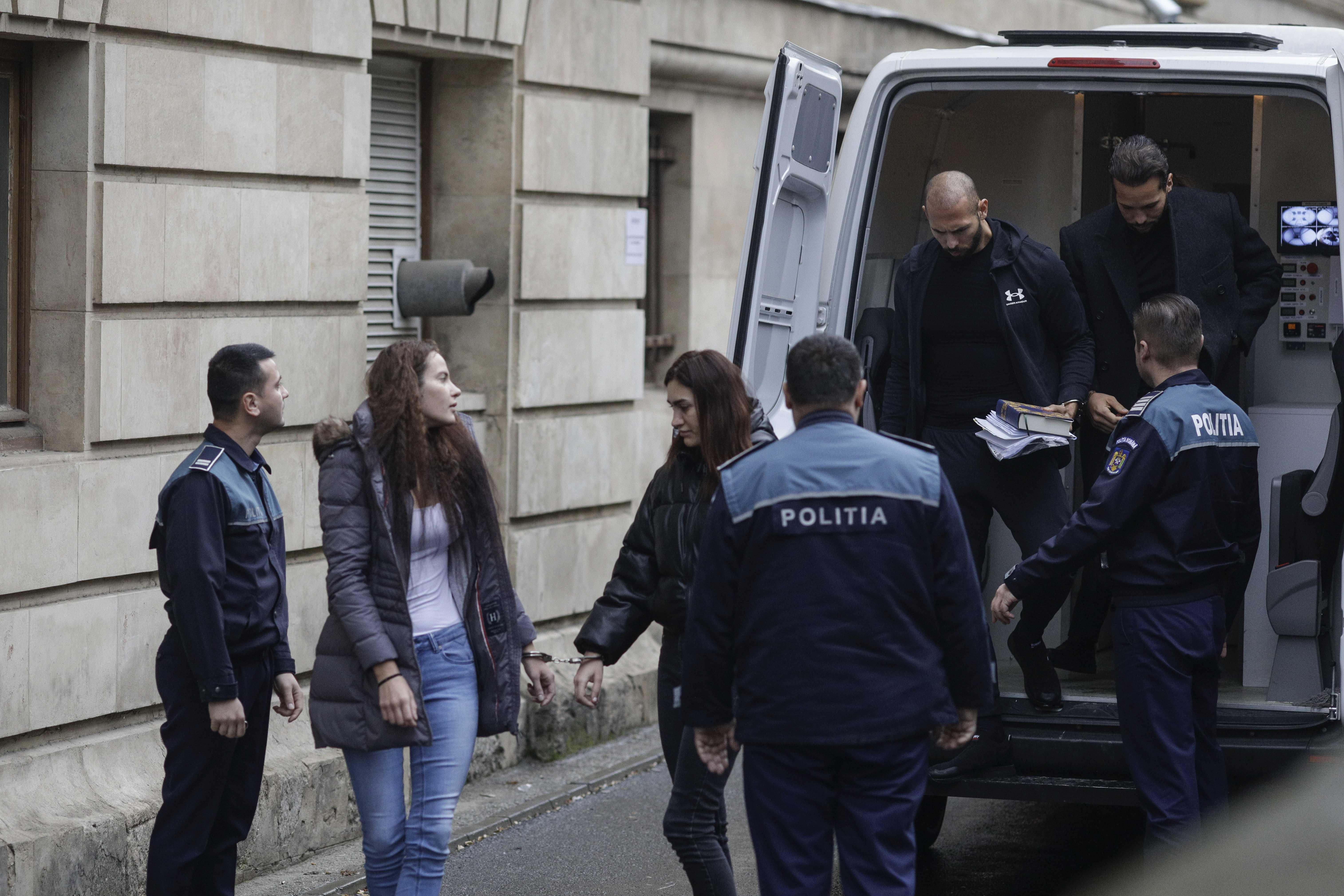 Fraţii Tate aduşi la instanţă cu duba, încătuşaţi. Andrew ţinea în mână un Coran