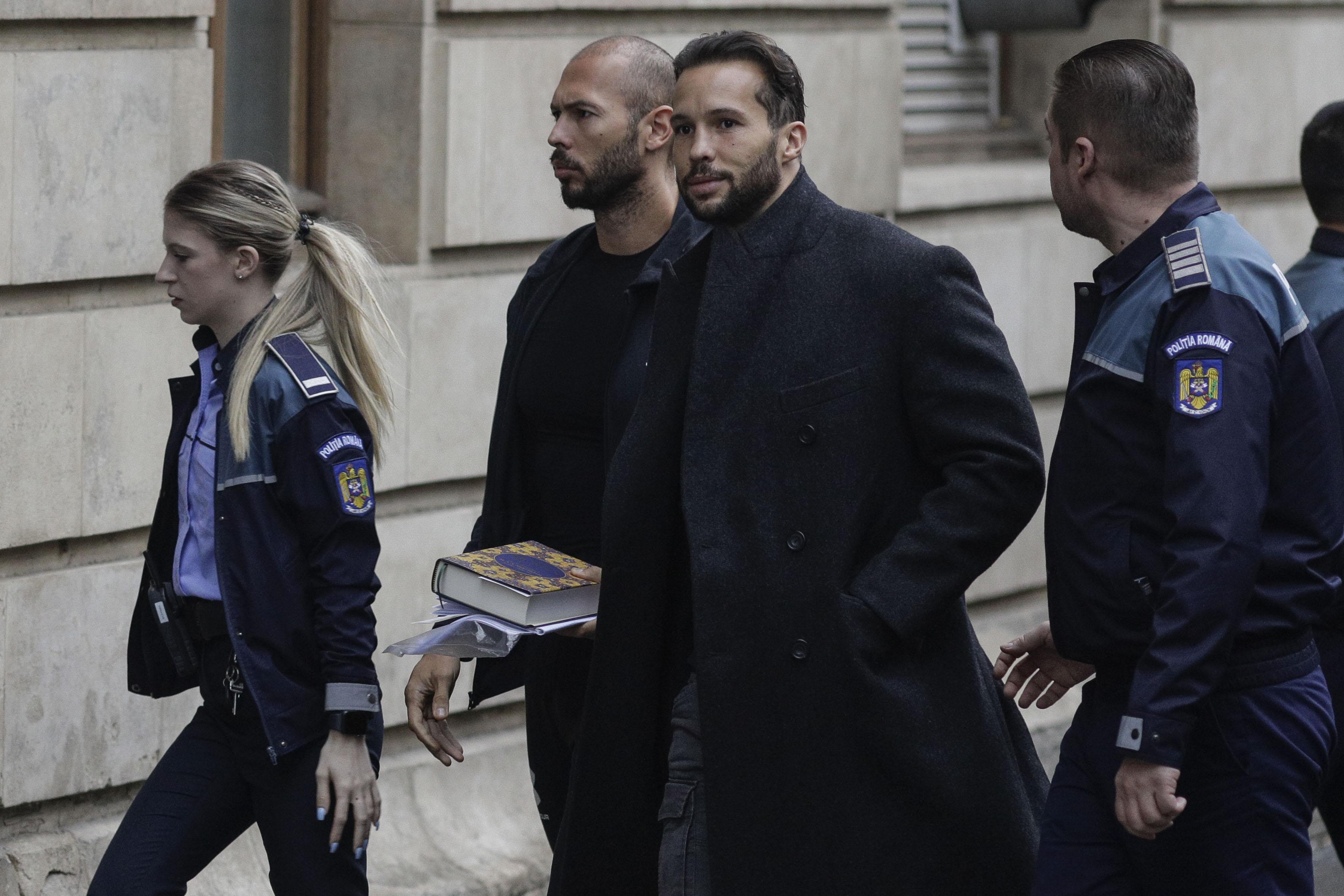 Fraţii Tate aduşi la instanţă cu duba, încătuşaţi. Andrew ţinea în mână un Coran