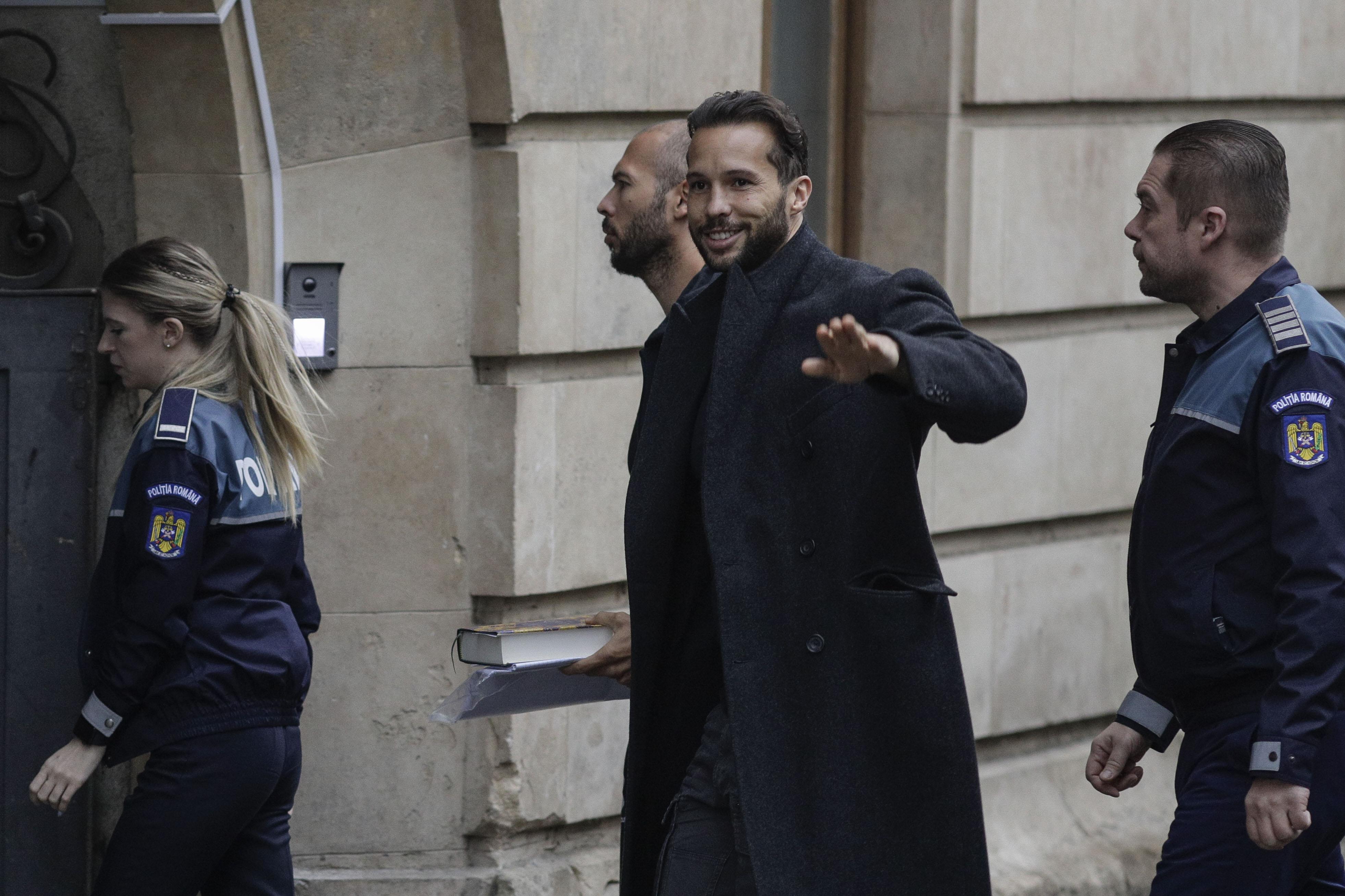 Fraţii Tate aduşi la instanţă cu duba, încătuşaţi. Andrew ţinea în mână un Coran