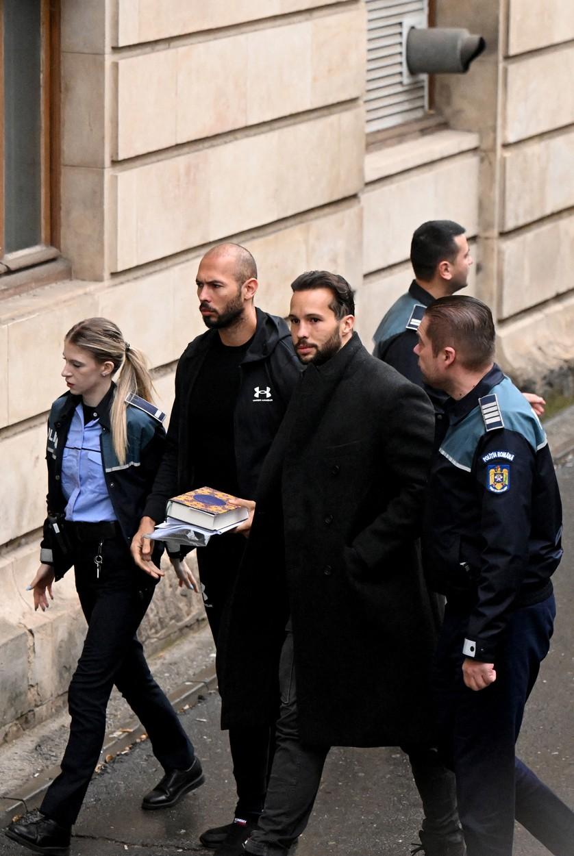 Fraţii Tate aduşi la instanţă cu duba, încătuşaţi. Andrew ţinea în mână un Coran